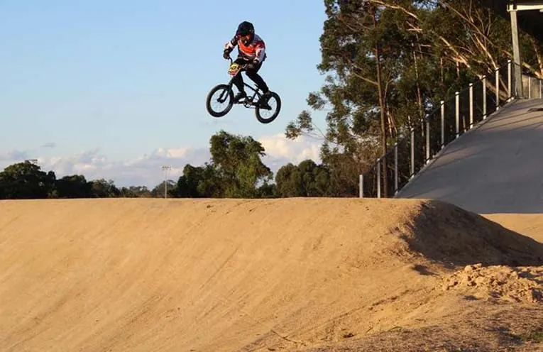 BMX rider in the air off a jump on a newly built dirt track